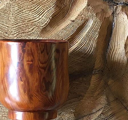 背景無塗装の木材にウレタン塗装のカップ